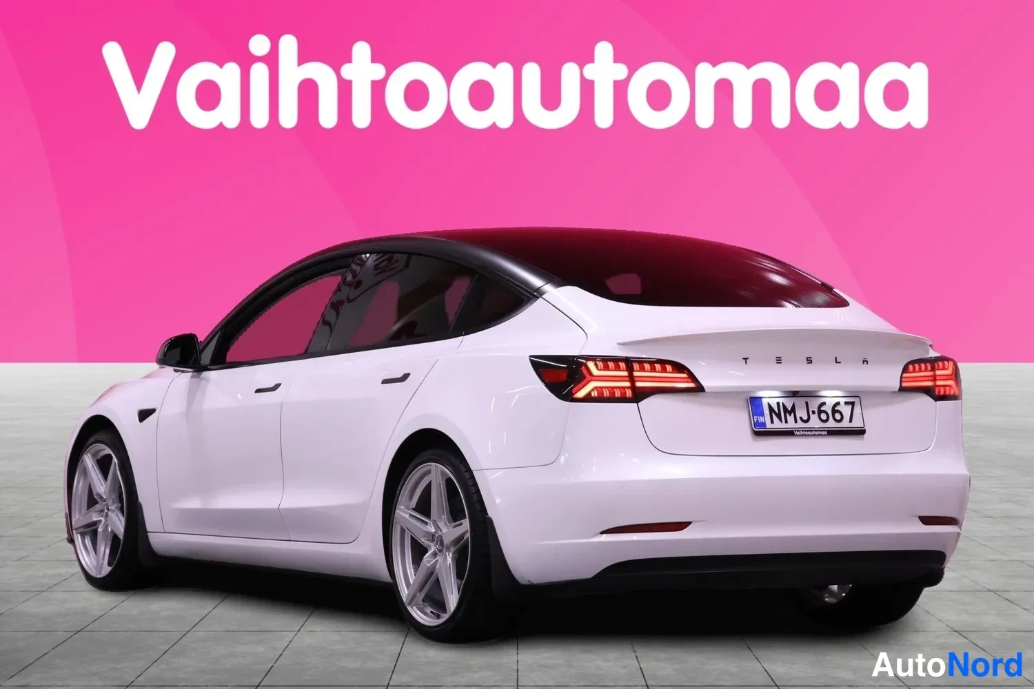 Takaviisto: Auton takakulma vasemmalta: valkoinen sedan, musta lasikatto, TESLA-takapaneeli ja rekisteri.