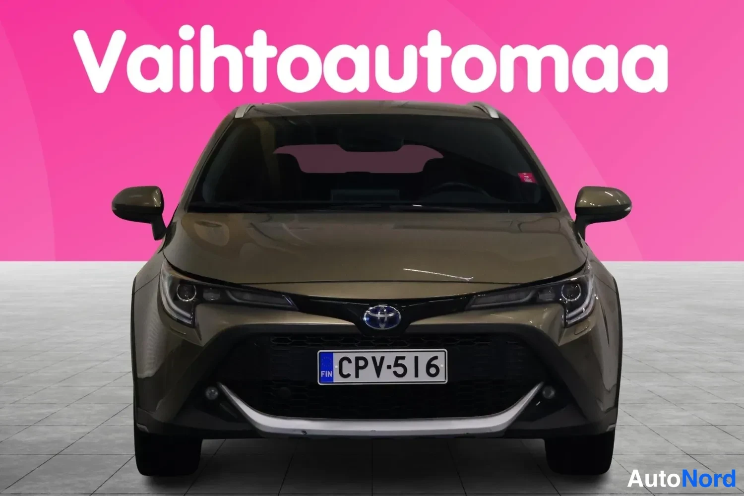 Edestä: Auto suoraan edestä kuvattuna, ruskea kori ja etupuskurissa valkoinen lisäke.