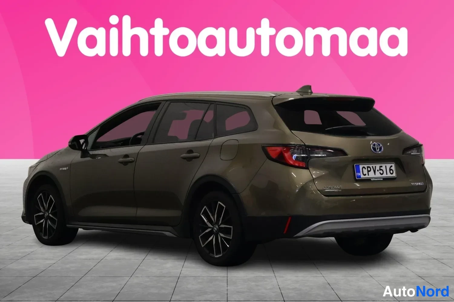 Takaviisto: Toyota Corolla Touring Sports -farmariauto takaviistosta, ruskean-kultainen koriväri, punaiset takavalot ja rekisteritunnus, pinkki tausta ja vaalea harmaa latt