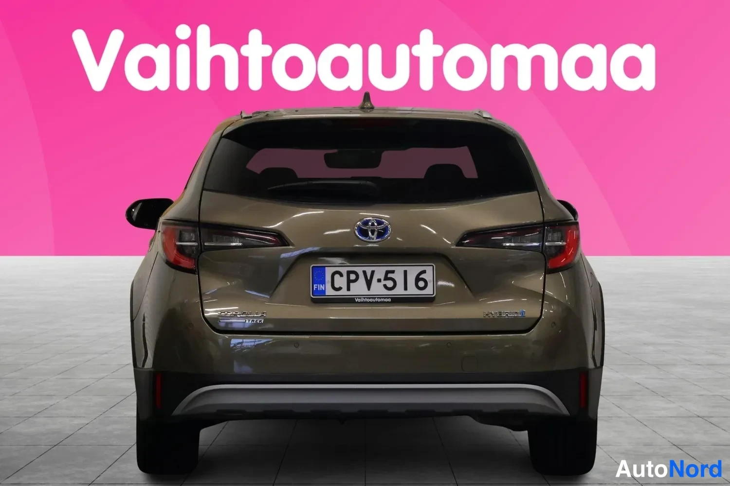 Takaa: Toyota Corolla Touring Sports -farmariauto suoraan takaa, ruskean-kultainen koriväri, punaiset takavalot, rekisteritunnus ja Toyota-logon keskeinen asento takal