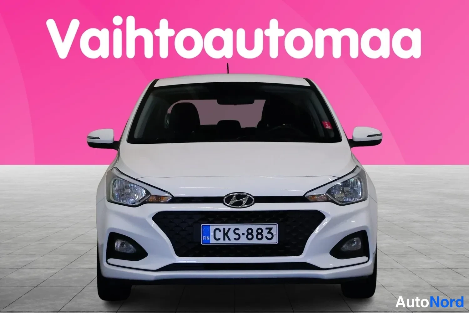 Edestä: Valkoinen henkilöauto suoraan edestä päin, rekisteri, pinkki Vahtoautomaa-tausta.
