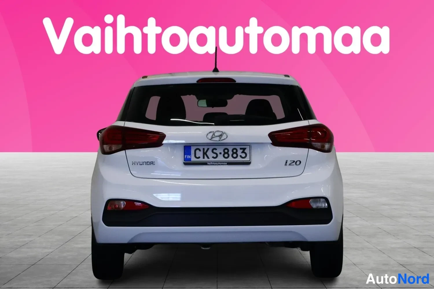 Takaa: Valkoisen Hyundain takanäkymä, rekisteri, HYUNDAI- ja i20-merkit takaluukussa.