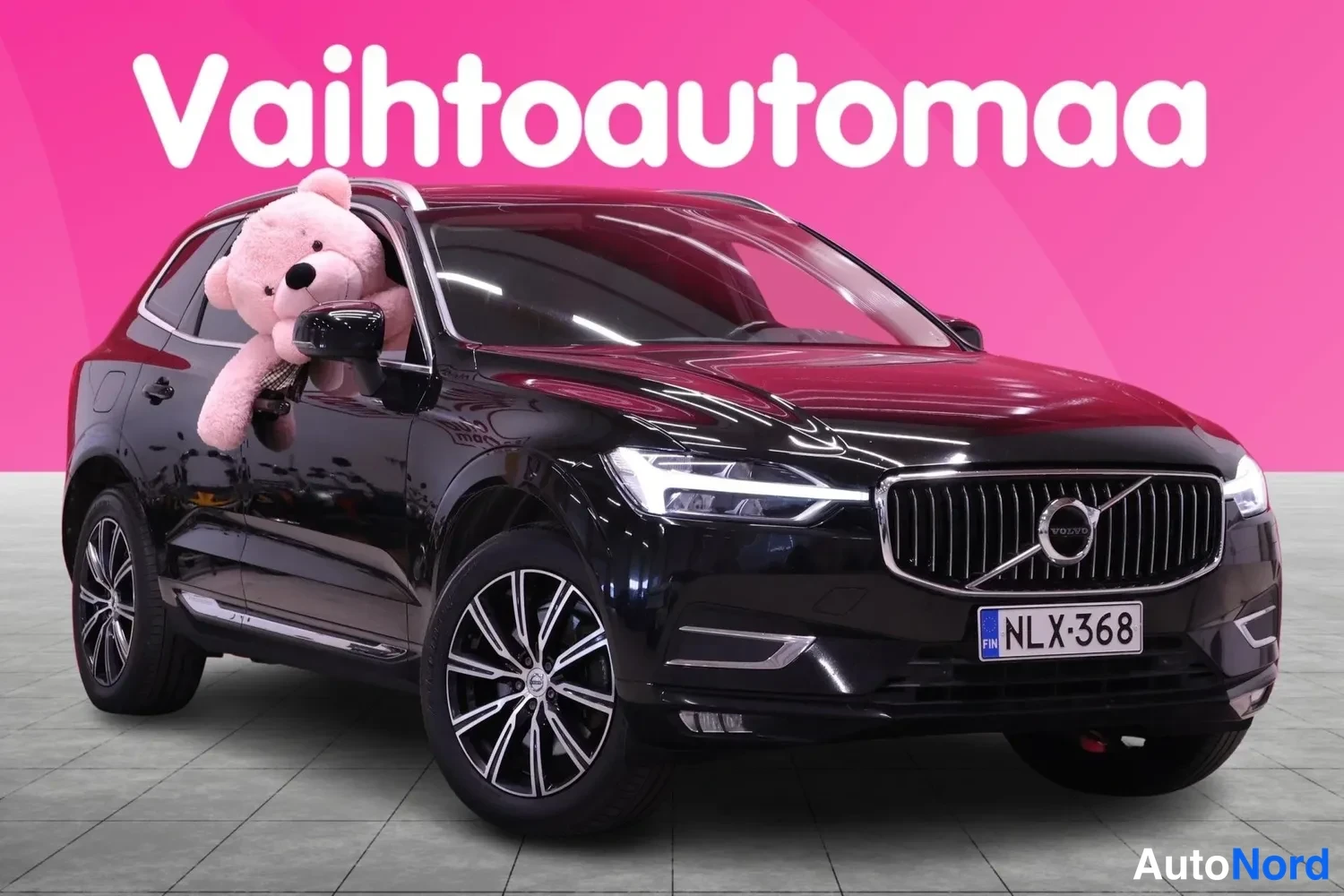 Etuviisto, nokka oikealle: Musta Volvo XC60 -farmarikulkuneuvo kolmesta neljäsosasta edestä oikealta, rekisterikilpi.