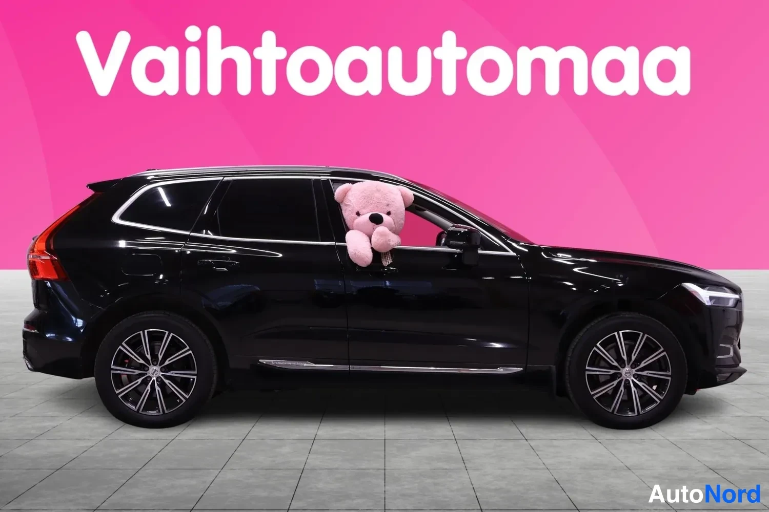 Sivulta: Mustan Volvo XC60:n sivukuva, vasemman sivun pitkä profiili, takarenkaat ja hopeiset vanteet näkyvät.