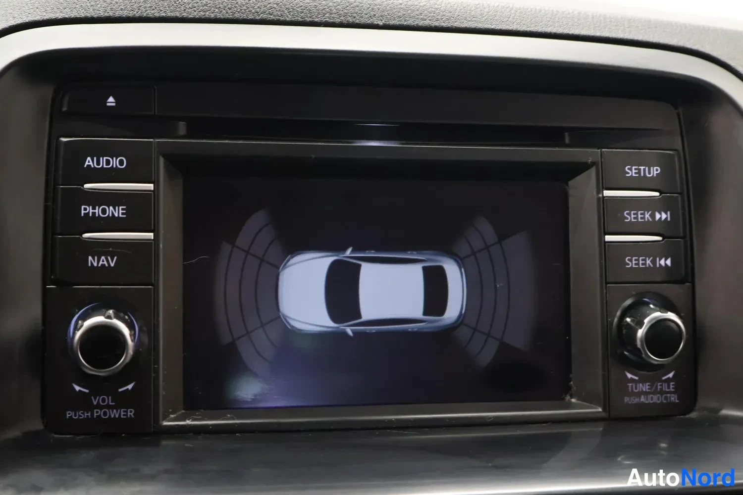 Yksityiskohta: Auton infotainment-näyttö, jossa on parkkitutkan kaavio auton ympärillä.