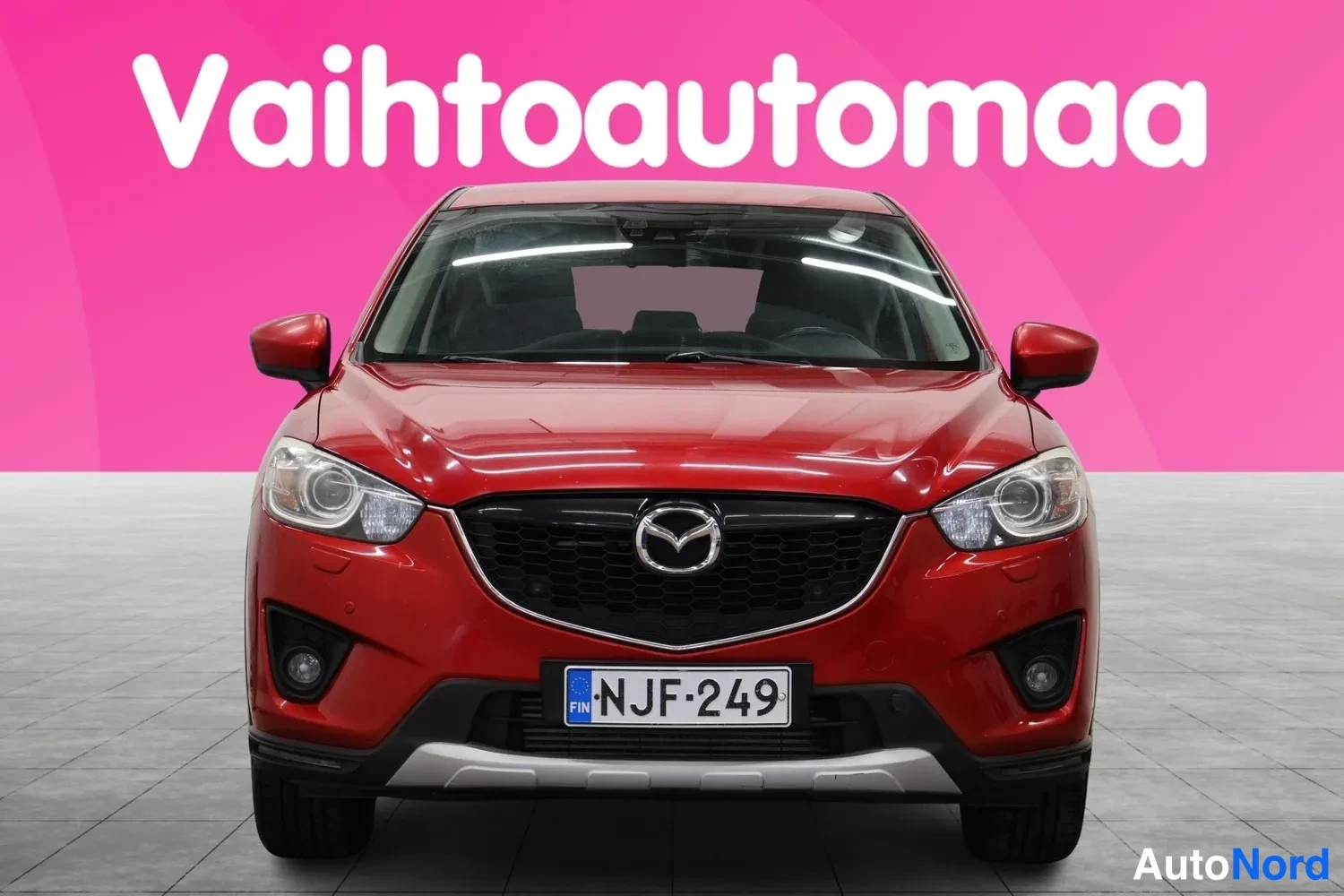 Edestä: Punaisen Mazda CX-5:n etupää suoraan edestä, etusäleikkö ja rekisterikilpi näkyvissä.