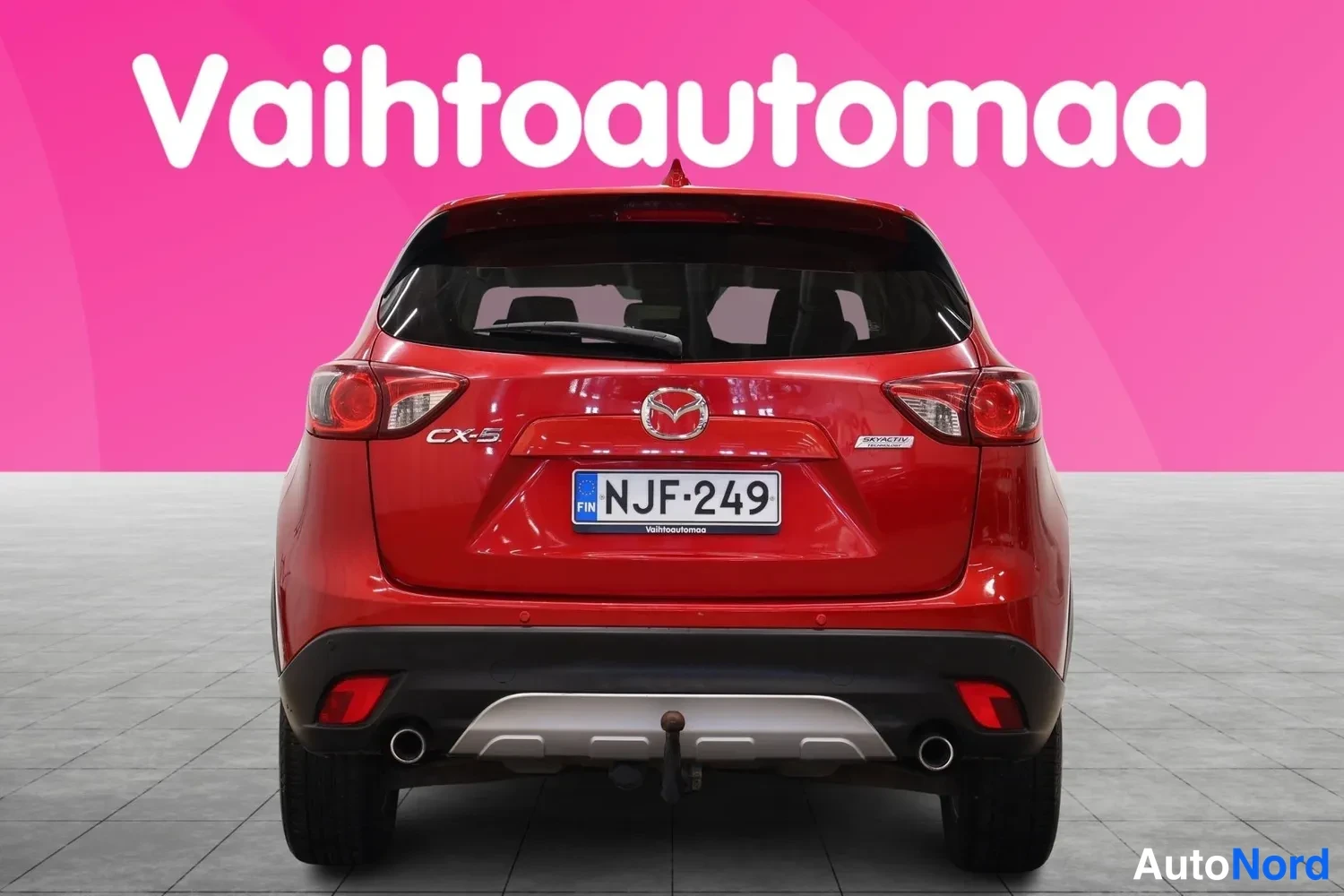Takaa: Punaisen Mazda CX-5:n suora takanäkymä, rekisterikilpi ja kaksinkertaiset pakoputket.