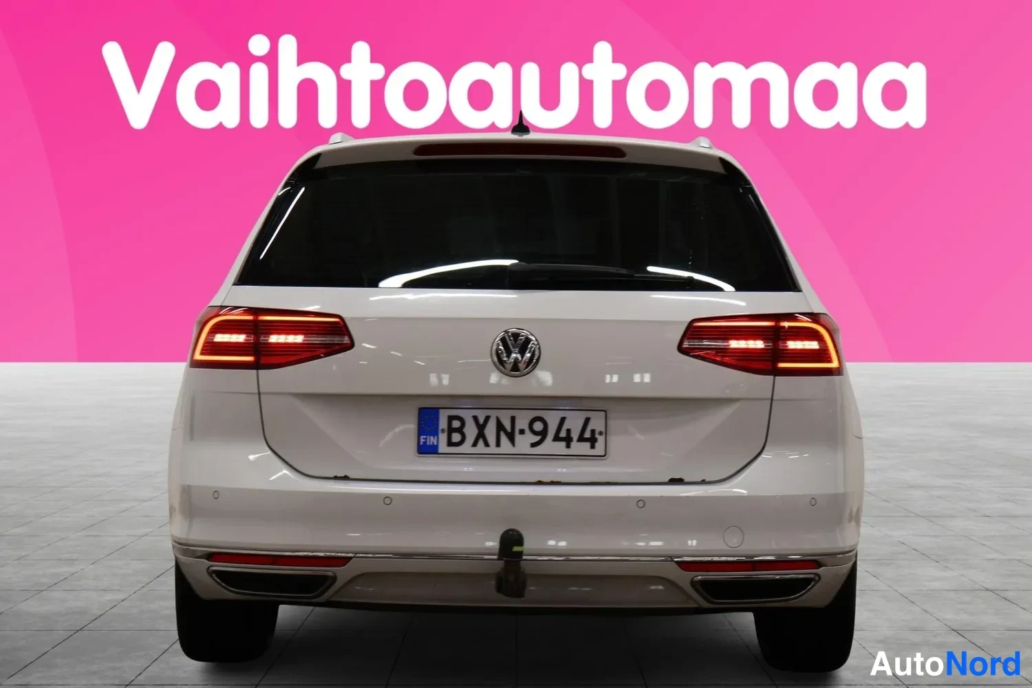 Takaa: Valkoisen farmariauton takanäkymä suoraan takaa: punaiset takavalot, VW-merkki, rekisterikilpi ja irrotettava vetokoukun kaula.