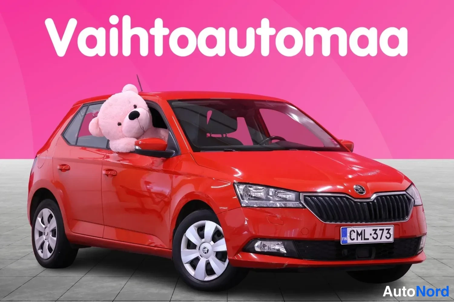 Etuviisto, nokka oikealle: Punaisen hatchback-auton etukulma etupyörän ja etupuskurin kanssa näkyvissä, rekisteritunnus.