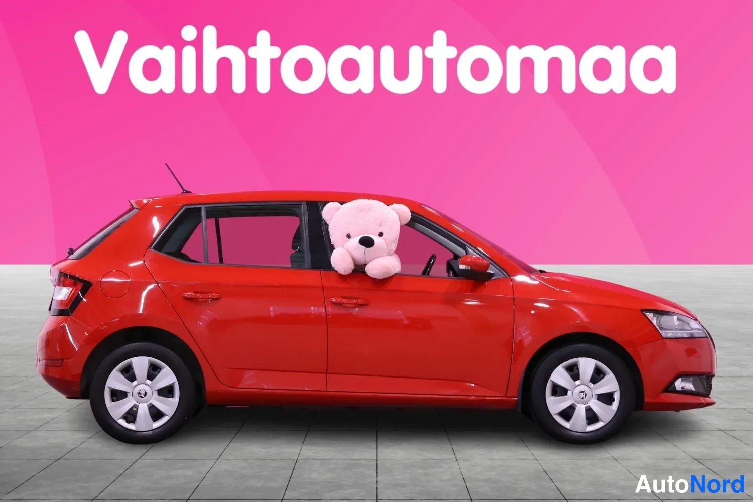 Sivulta: Punaisen hatchback-auton sivuprofiili vasemmalta katsottuna, molemmat kyljet ja etupyörä näkyvissä.