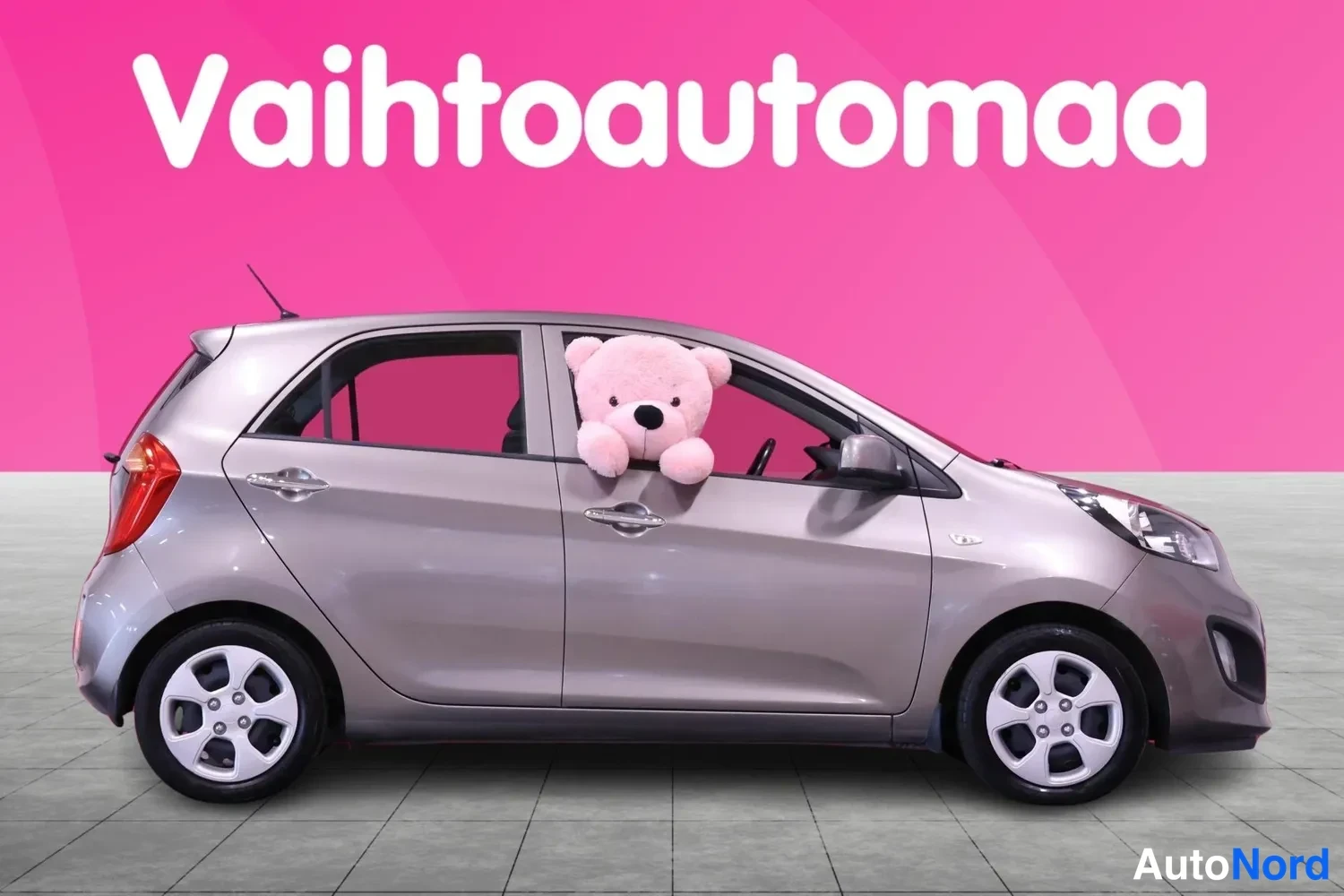 Etuviisto, nokka oikealle: Kia Picanto -henkilöauto sivukulmassa, keula oikealla, pehmolelu takaikkunassa.