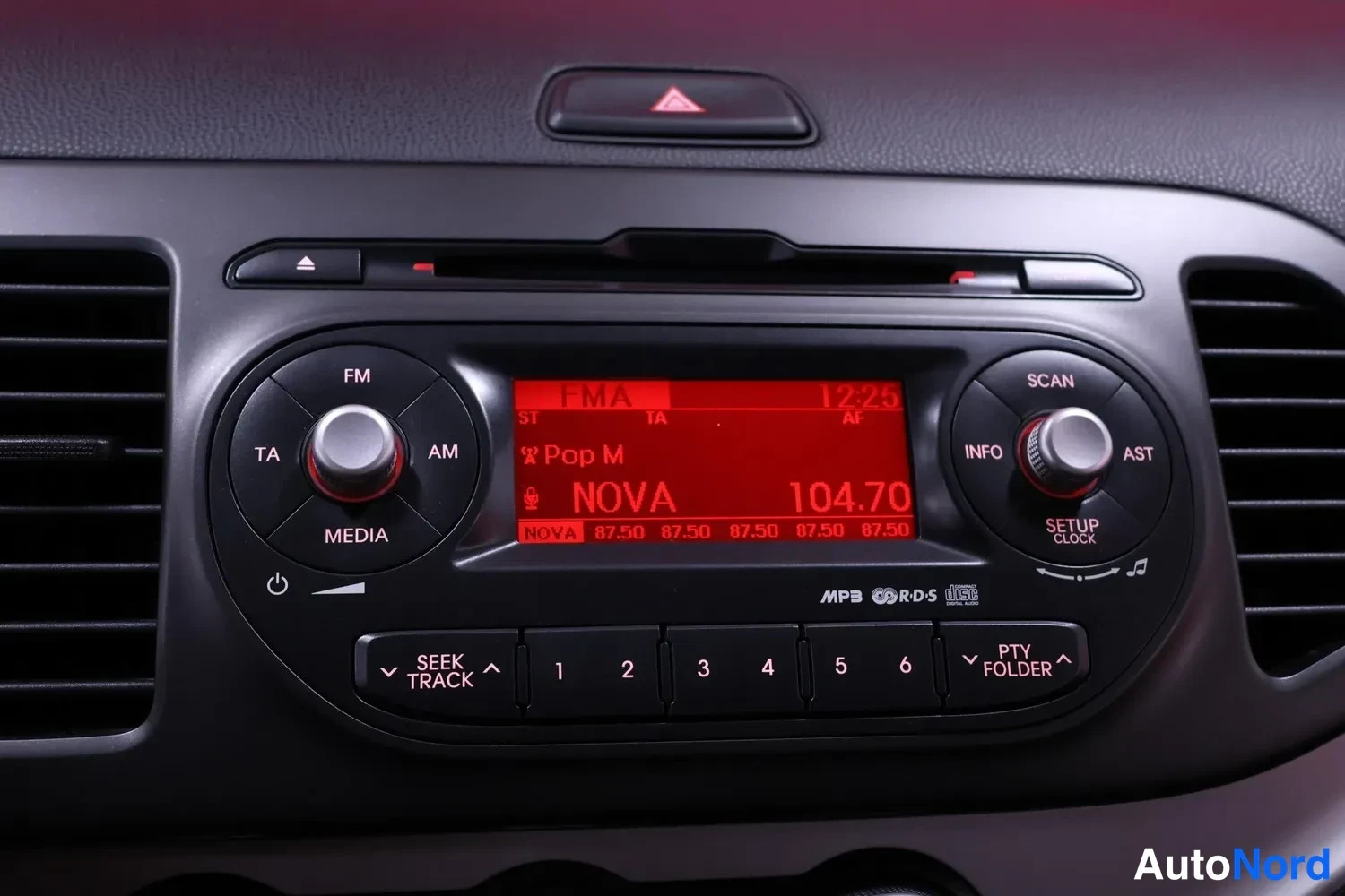 Muu: Keskikonsolin radio, jolla näytössä lukee NOVA 104.70 ja painikkeet SEEK TRACK, MEDIA, SCAN.