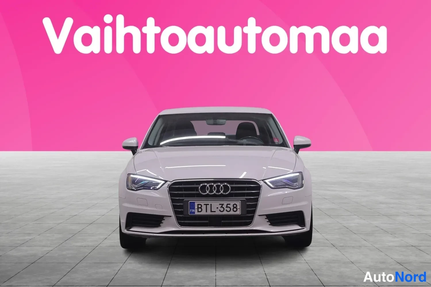 Edestä: Valkoinen Audi-sedan suoraan edestä, rekisterikilpi, sisätilat näkyvät vain läpikuultavasti