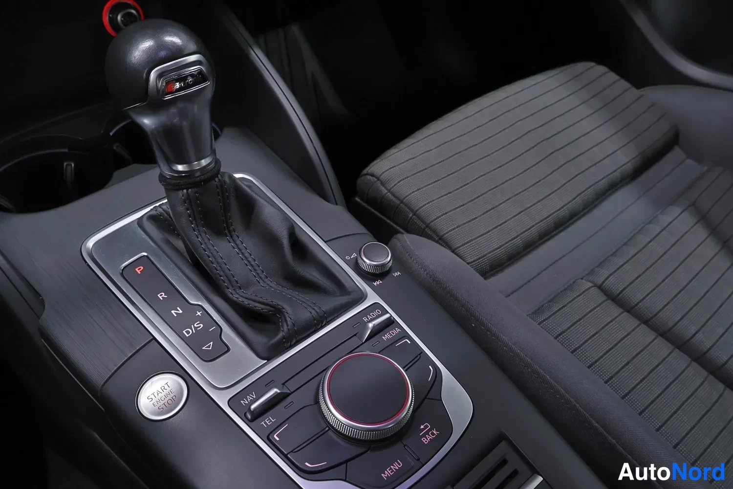 Etuistuimet: Center console interior view with automatic gear selector lever in 'P' position marked by red light. Below the shifter are navigation and media controls includi
