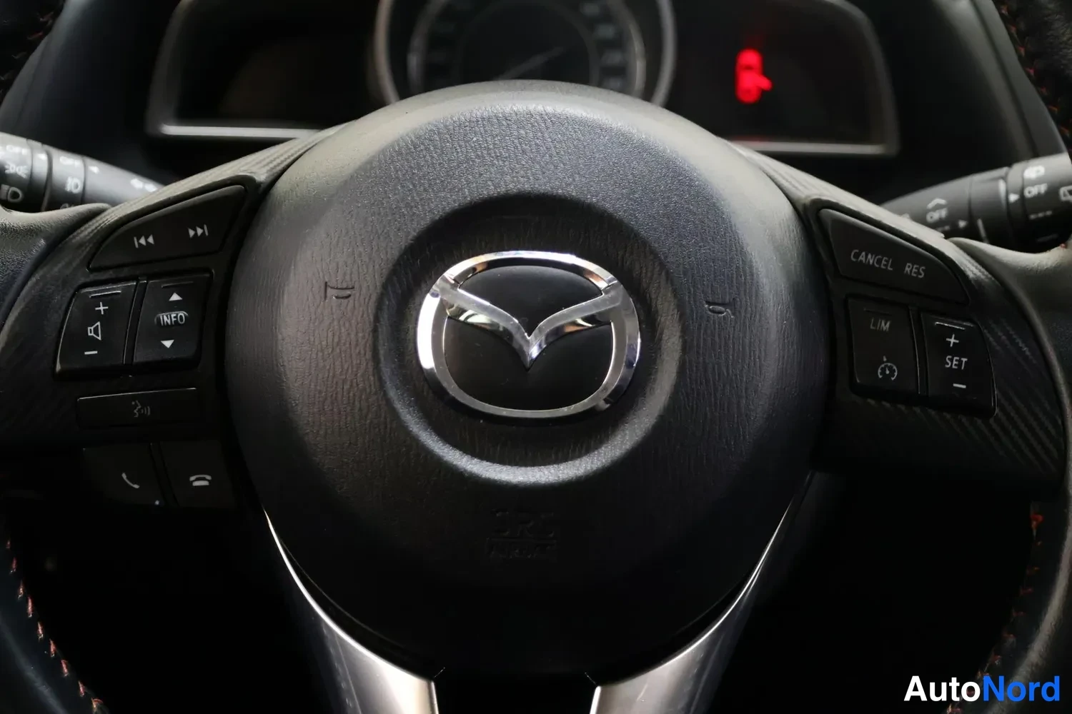 Muu: Mazda-ohjauspyörä, jonka puhelinlogo näkyy ja nappirivistöt: INFO, puhelu, CANCEL RES, LIM, SET