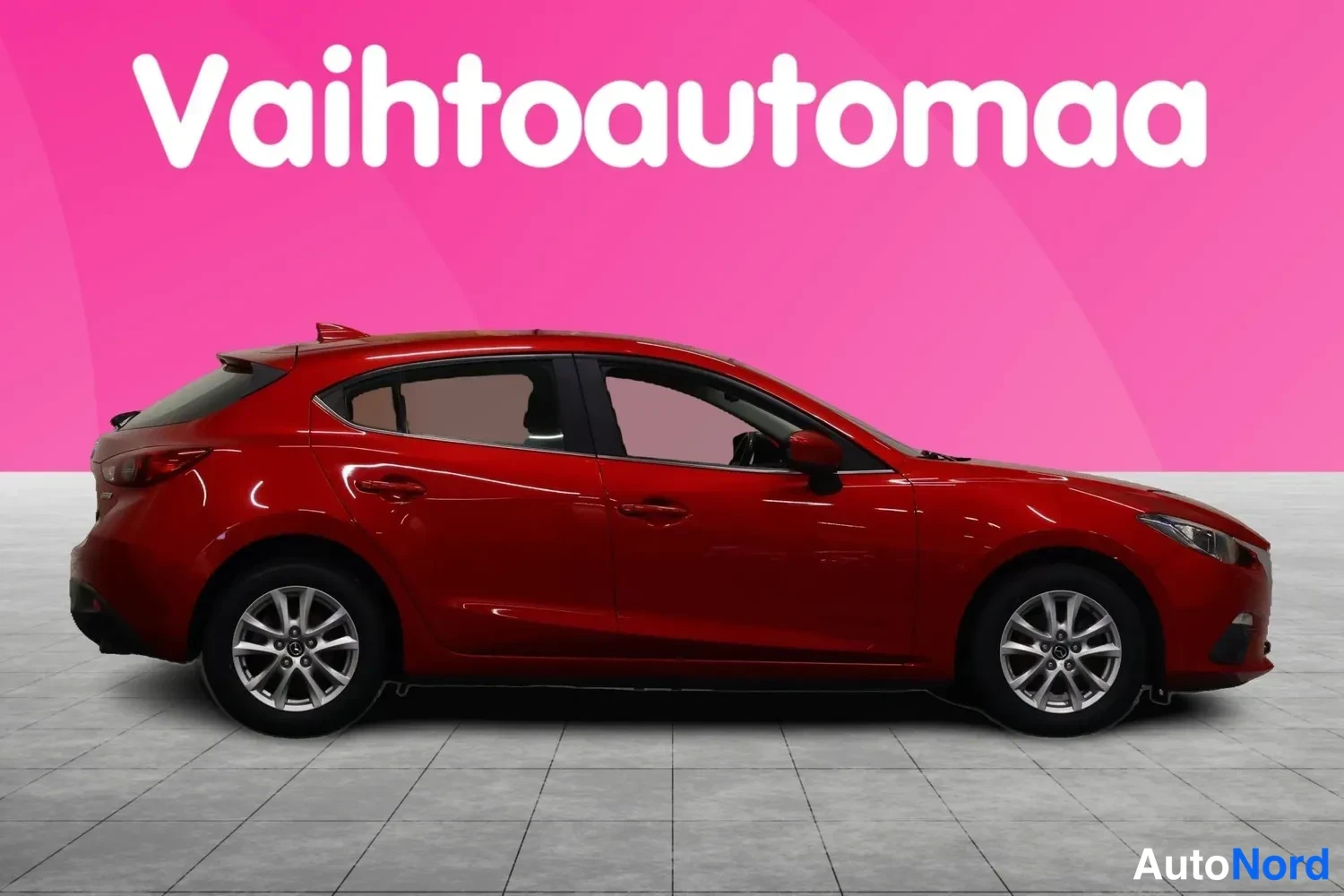 Etuviisto, nokka oikealle: Punainen viistoperä Mazda 3 etukolmannes oikealta nähtynä studiotaustaa vasten.