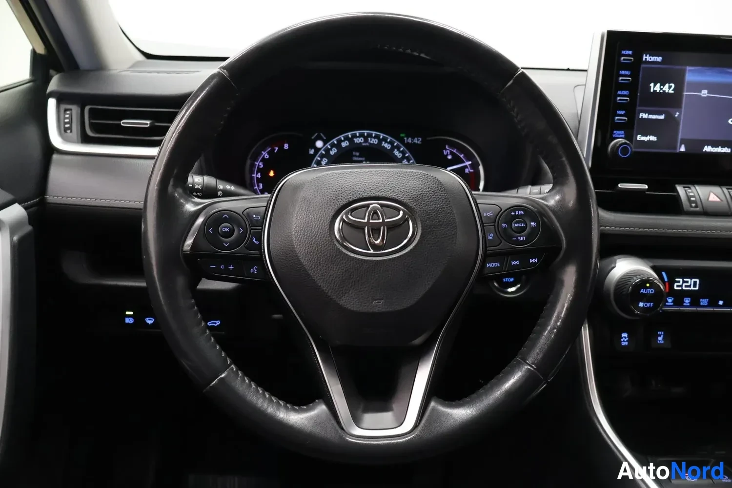 Muu: Ohjaamon sisäkuva: Toyota-ohjauspyörä ja mittaristo, oikealla medianäyttö ja autonäyttö ajassa 14:42.