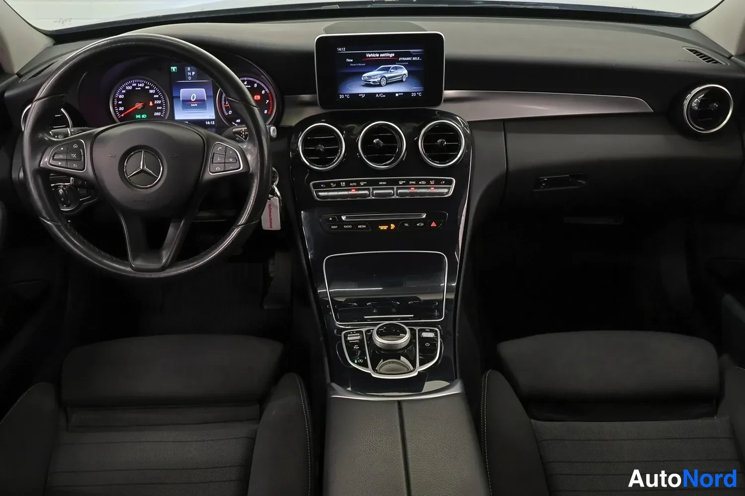 Edestä: Mercedes-Benzin ohjaamo: ratin takana analogiset mittarit, keskikonsolissa irtonäyttö, kolme pyöreää ilmastointiaukkoa, nappipaneeli ja COMAND-ohjainkärry, must