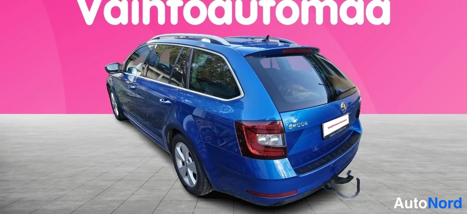 Takaviisto: Sininen farmariauto takaa vasemmalta kolmesta neljäsosasta kuvattuna; takavalo, jatkojohto ja takapuskuri näkyvät.