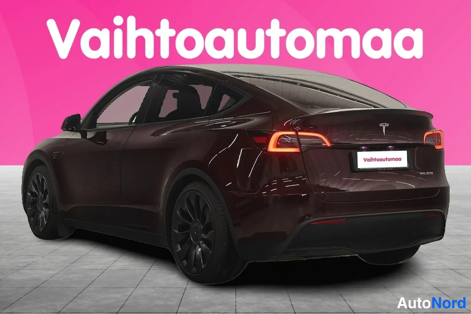 Takaviisto: Tesla Model Y takaviistosta kuvattuna, takavalot ovat päällä ja rekisterin paikalla on Vaihtoautomaa-kyltti.