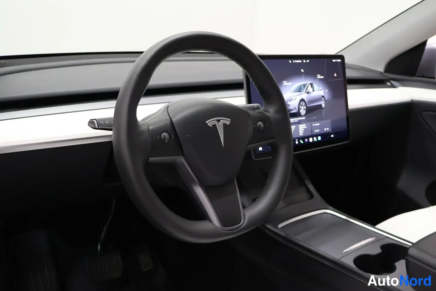 Yksityiskohta: Tesla-merkitty ohjauspyörä ja keskinäyttö, joka näyttää ajoneuvon tietoja.