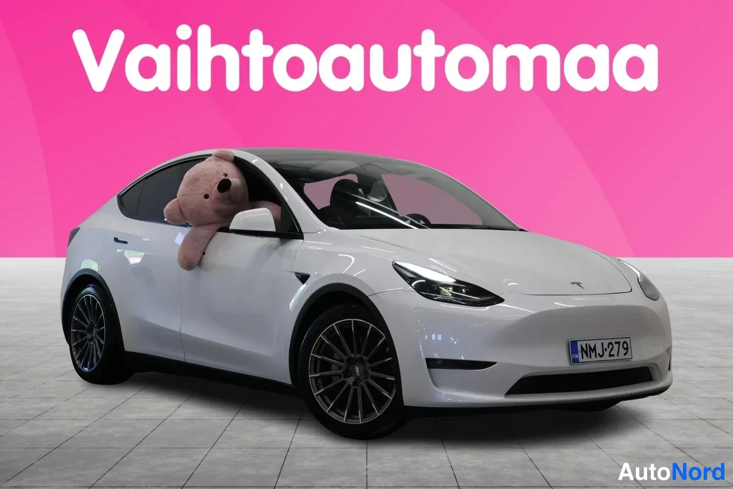 Etuviisto, nokka oikealle: Valkoinen Tesla Model Y kolmessa neljännessä etunäkymässä, keulaa oikealle, rekisteritunnus.