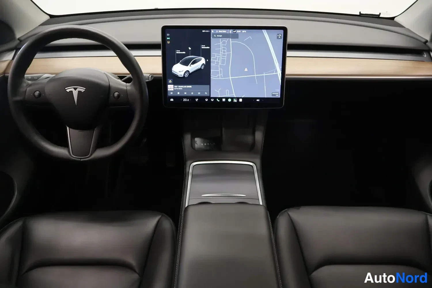 Muu: Tesla-automatin ohjaamo: nahkainen ohjauspyörä, keskirivin kosketusnäyttö kartta- ja ajoneuvonäkymällä, mustat etuistuimet ja puenvärinen kojelaudan koriste.