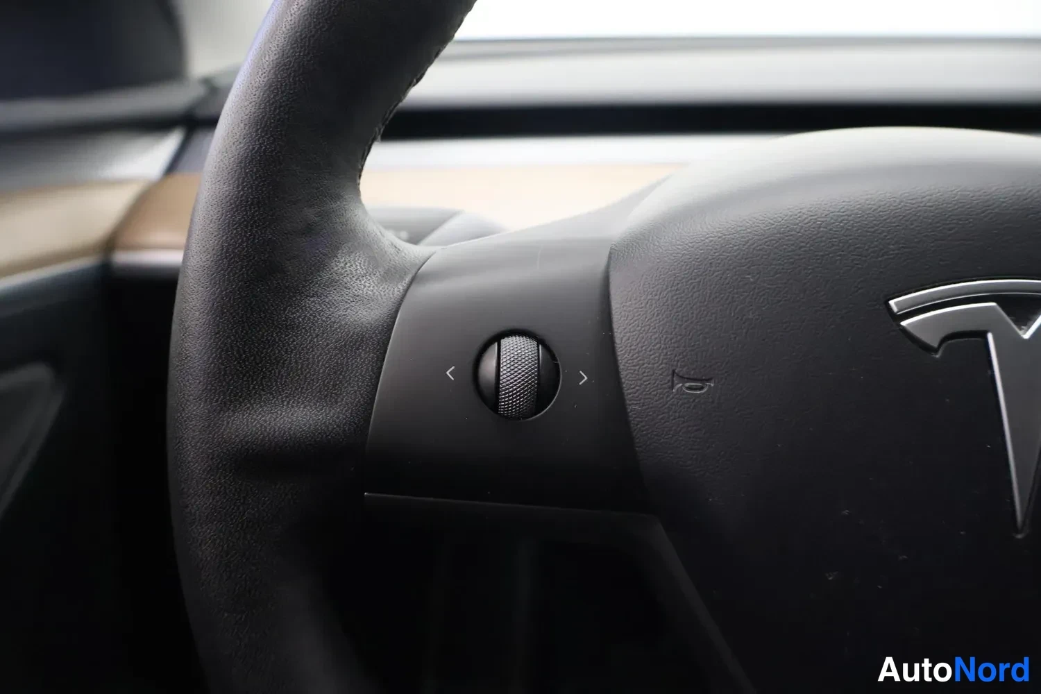 Muu: Lähikuva Tesla-ohjauspyörän vasemmasta puhallusaukko- ja vieritysnapeista sekä tuulilasinpyyhkimen säätimestä.