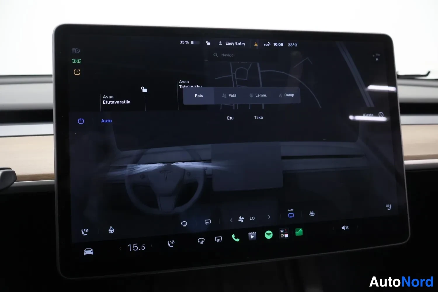 Muu: Tesla Model Y:n kosketusnäyttö, jossa on avattuna ilmastoinnin ja vetokoukun asetukset, akun varaus 33 % ja ulkolämpötila 23 °C.