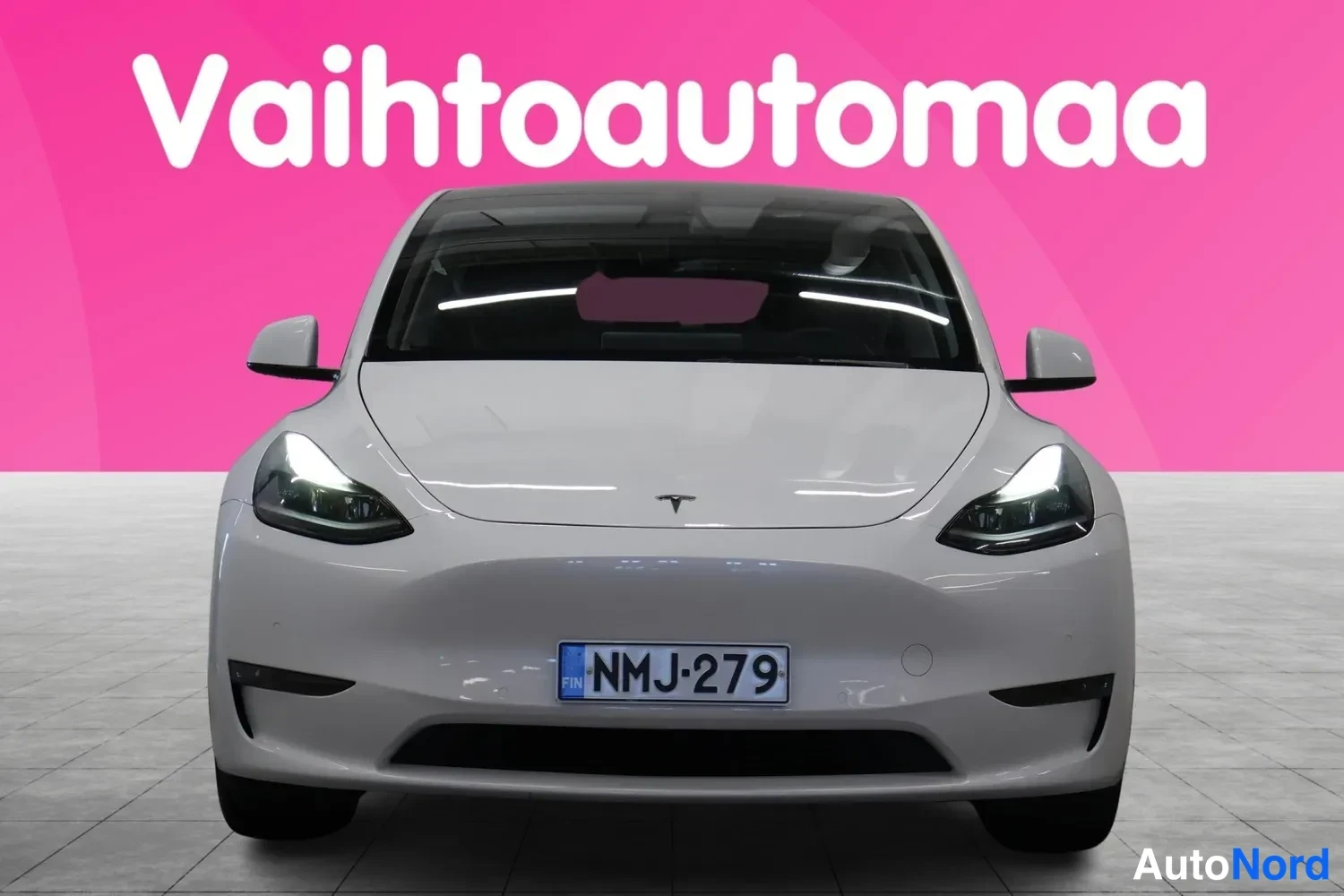 Edestä: Valkoinen Tesla Model Y suoraan edestä, rekisteritunnus.