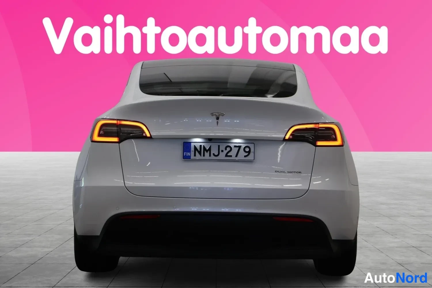 Takaa: Tesla Model Y -henkilöauton takanäky suoraan takaa, valot päällä, rekisterikilpi.