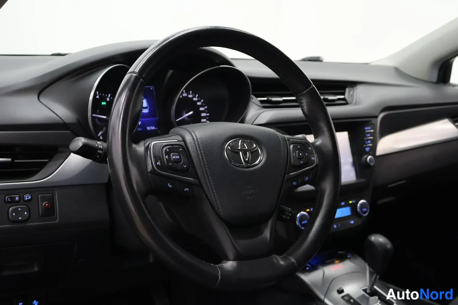 Muu: Kuljettajan näkymä ohjaamoon: Toyota-merkillä varustettu ohjauspyörä, kojelauta, infotainment-näyttö ja automaattivaihteiston valitsin.