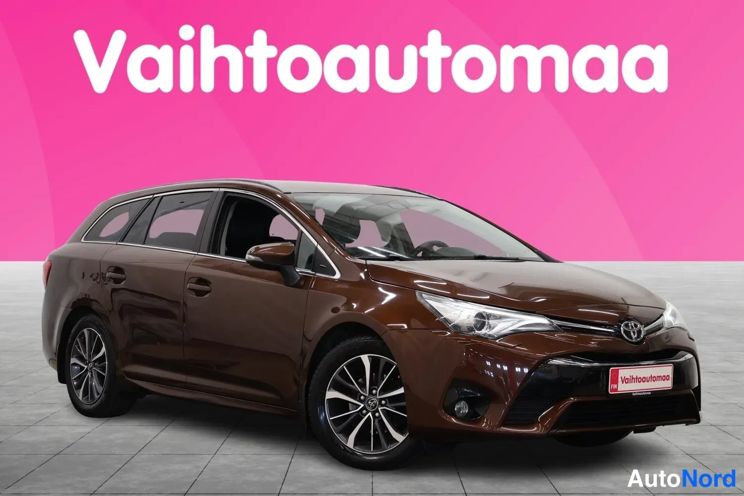 Etuviisto, nokka oikealle: Ruskea farmariauto kolmivaihekulmaisessa etunäkymässä, keula oikealla, showroom-taustalla.