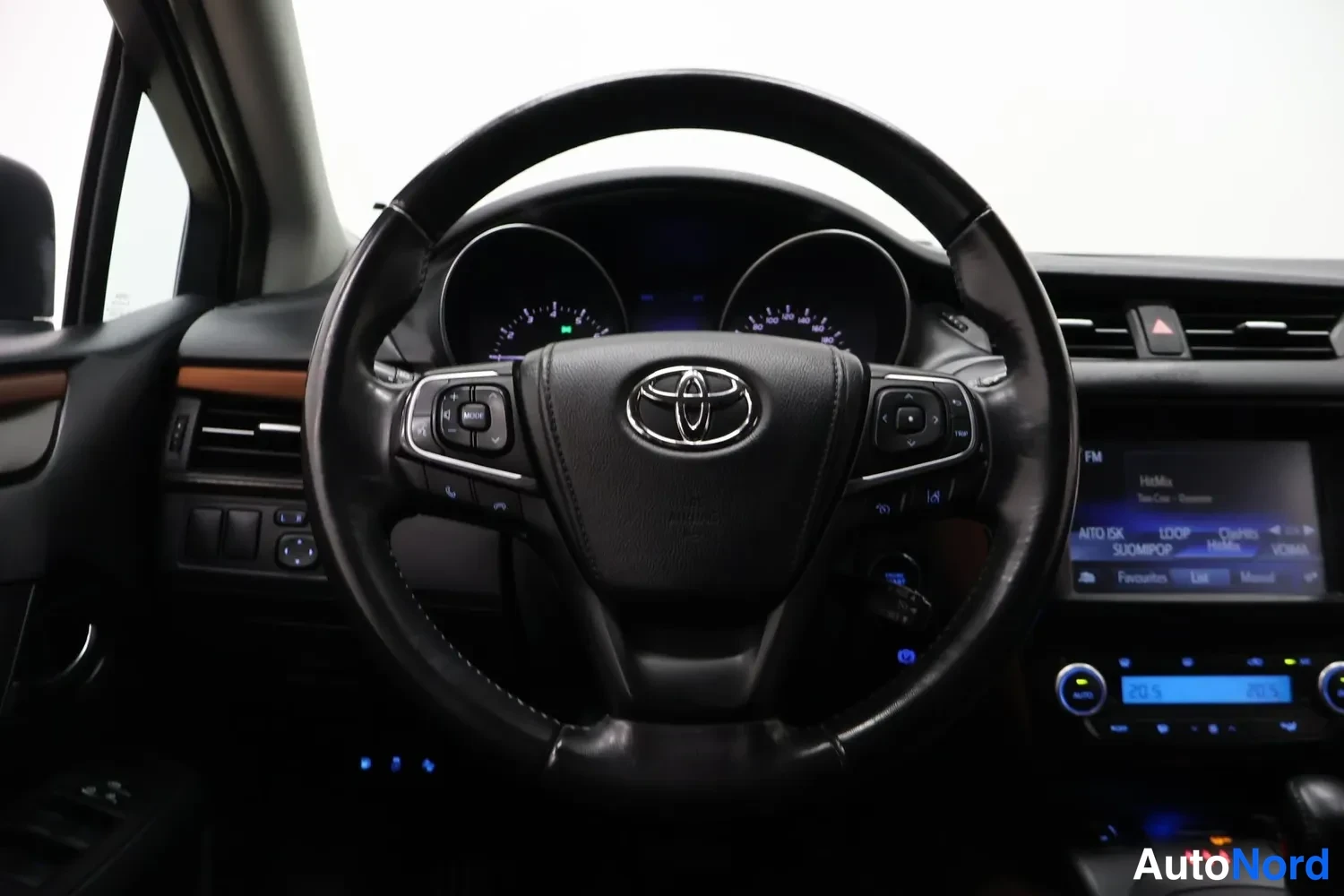 Yksityiskohta: Etusijoilta kuvattu ohjaamo: Toyota-ohjauspyörä, mittarit, infotainment-ruutu ja automatisoidun vaihteiston valitsin.