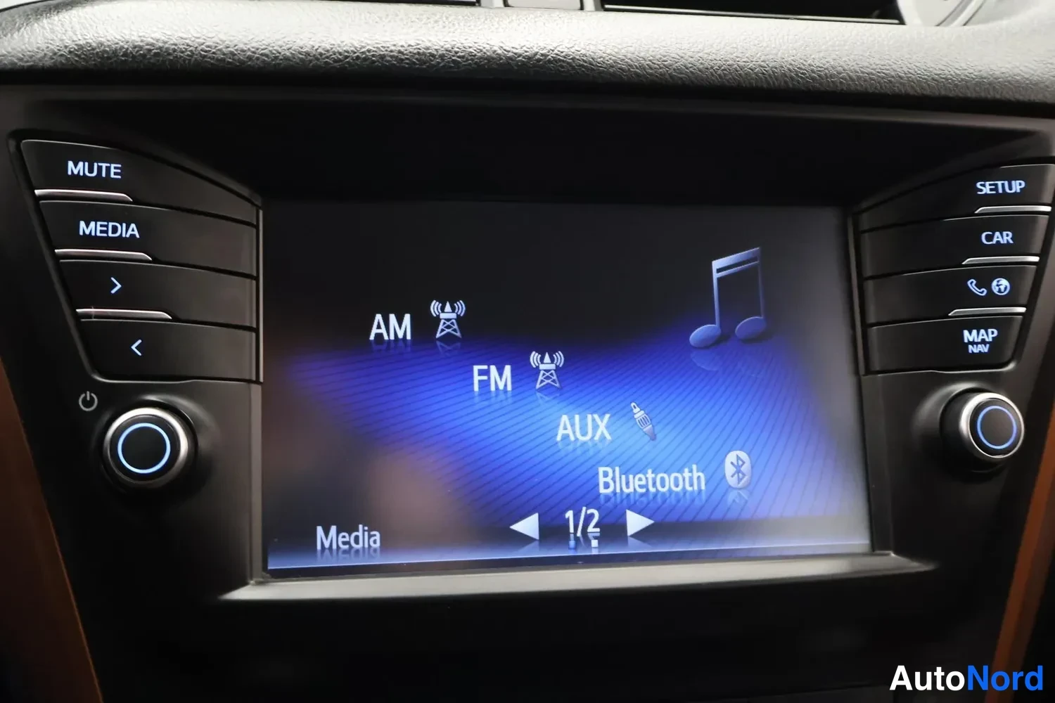 Yksityiskohta: Viihdejärjestelmän näyttö näyttää mediatulostusvalikossa AM-, FM-, AUX- ja Bluetooth-merkinnät.