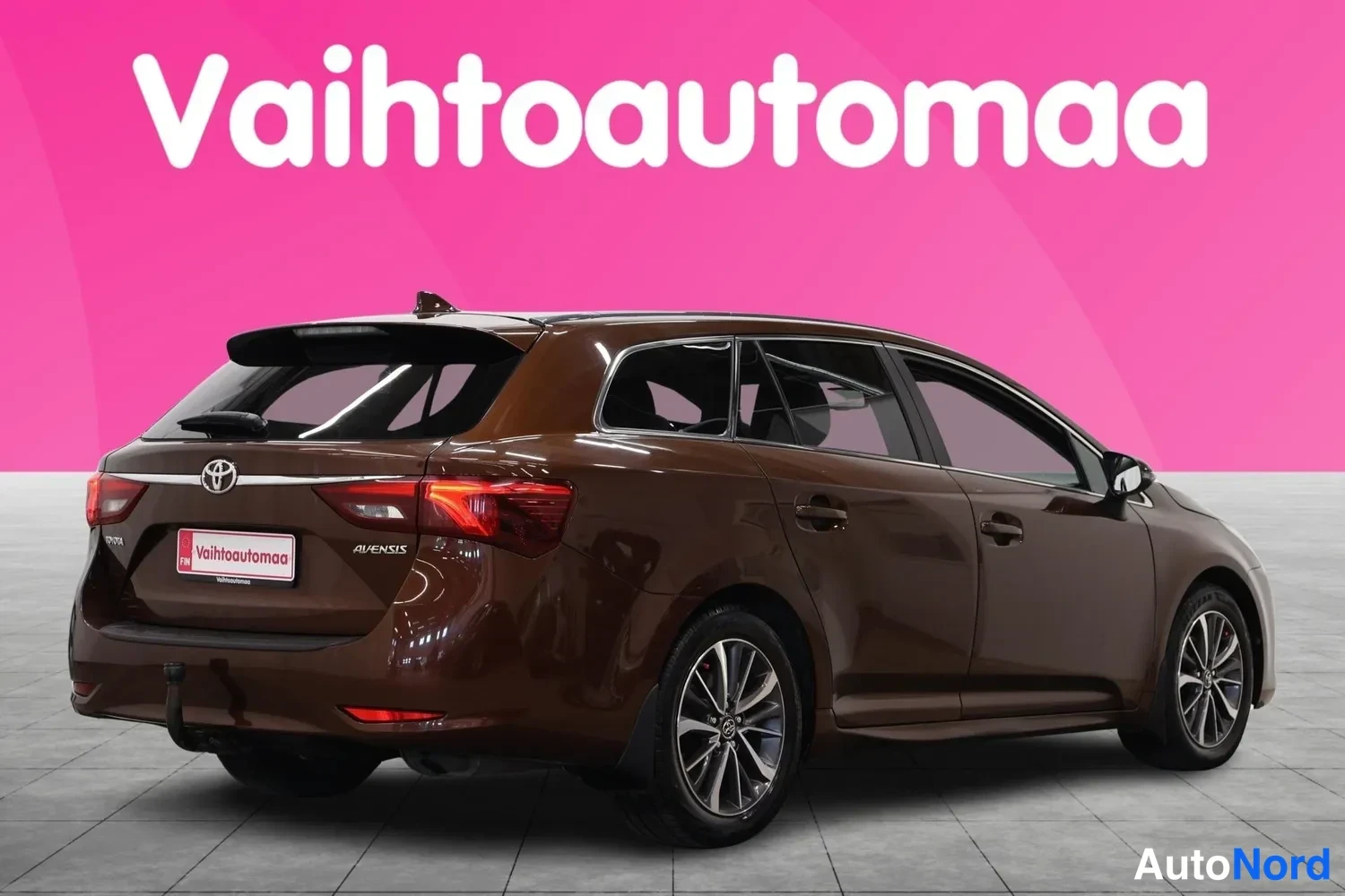 Takaviisto: Ruskean Toyota Avensis -farmarin takaosasivukulma oikealta, avensis-teksti takaluukussa ja Puolan rekisterikilpi.