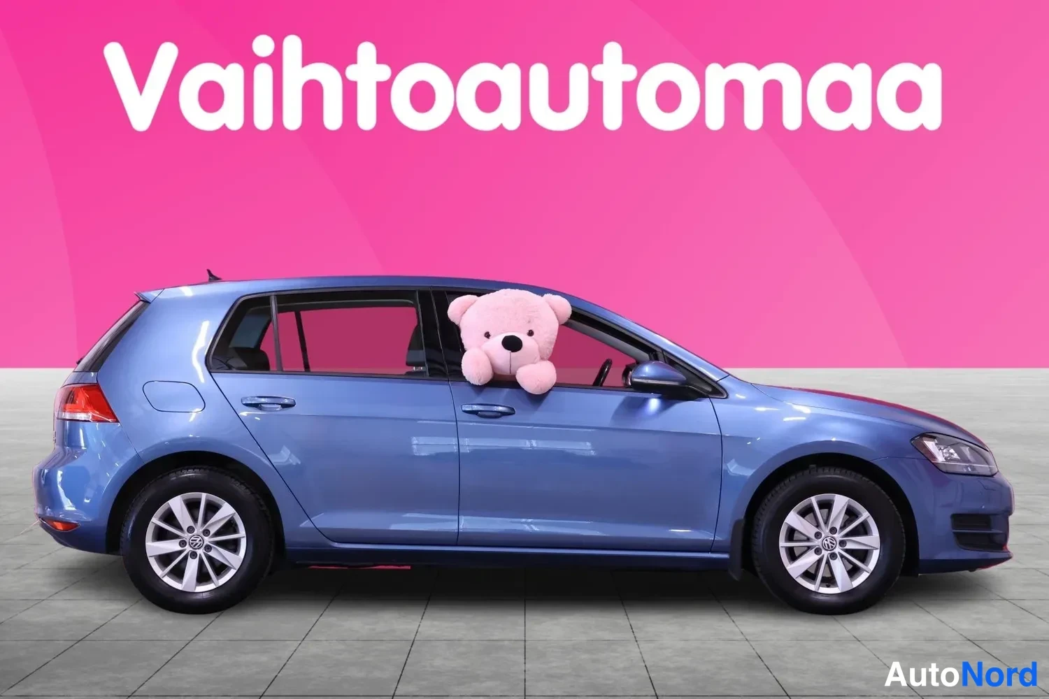 Sivulta: Sininen Volkswagen Golf sivulta oikealta kuvattuna, pehmolelu ikkunassa
