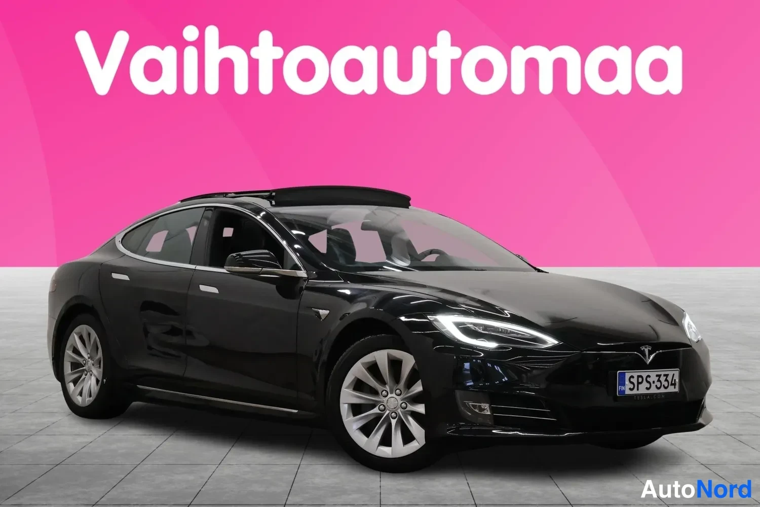 Etuviisto, nokka oikealle: Mustan Tesla Model S -sedanin etukulmakuva vasemmasta sivusta, rekisterikilpi, taustana pinkki mainospinta.