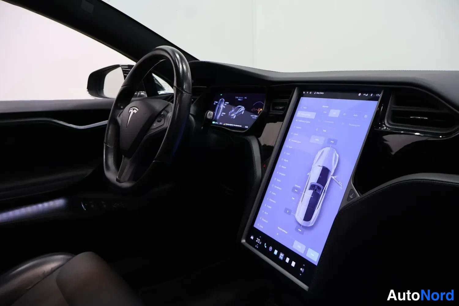 Muu: Tesla-logollinen ohjauspyörä, mittarinäyttö ja suuri pystyyn asennettu kosketusnäyttö, joka näyttää auton asetukset ja ajoneuvon kuvan.