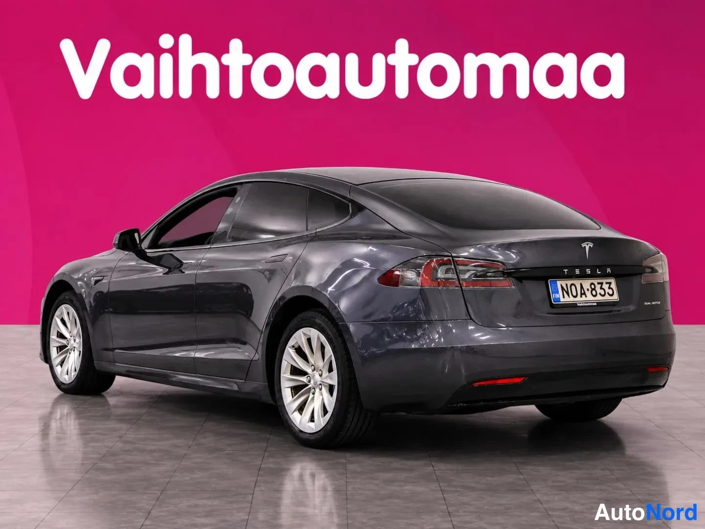 Takaviisto: Tummansininen Tesla Model S -sedan takaokolikuva vasemmalta, rekisteritunnus ja Tesla-merkki takaluukussa.
