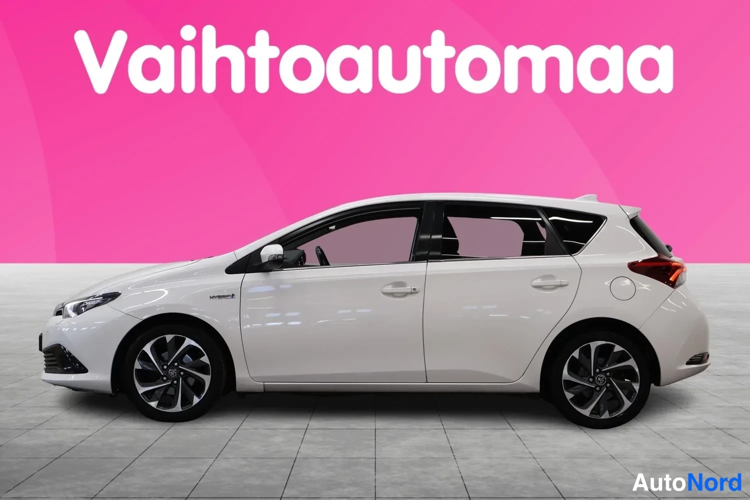 Sivulta: Valkoinen viisiovinen hatchback sivuprofiilista, harmaat kevytmetallivanteet, vaaleansininen tausta.