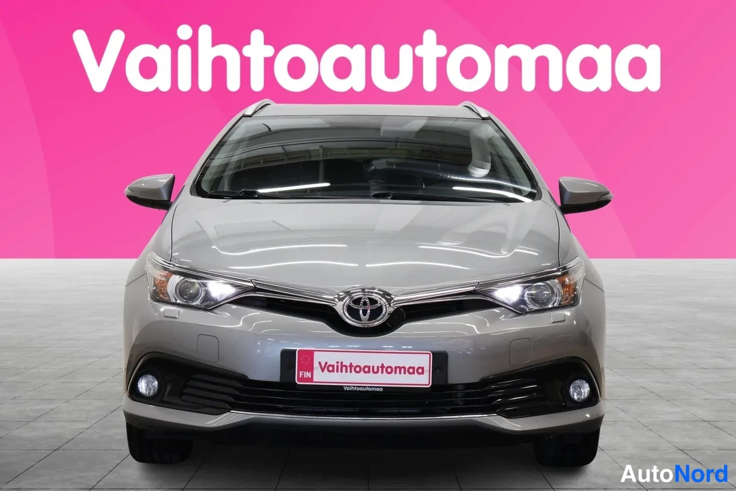 Edestä: Auto suoraan edestä, hopeanharmaa kori, Toyota-merkki, ajovalot ja etupuskuri näkyvissä.
