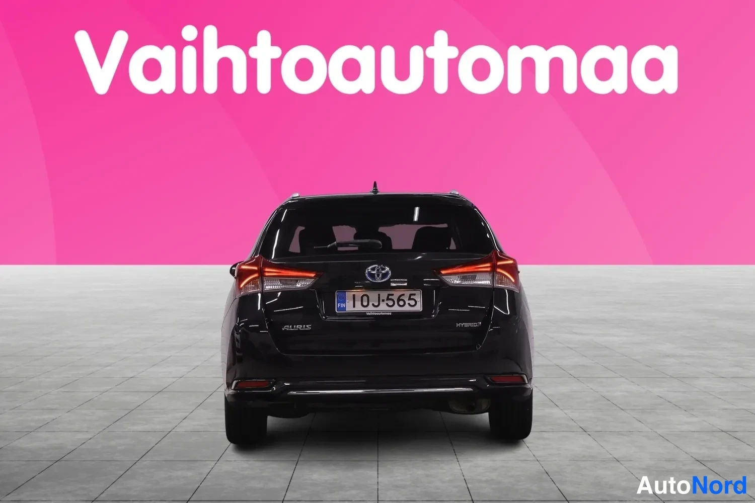 Takaa: Mustan Toyota Auris -farmariauton takaosa suoraan takaa, rekisteritunnus 10J-565, Auris- ja Hybrid-merkinnät takaluukussa.