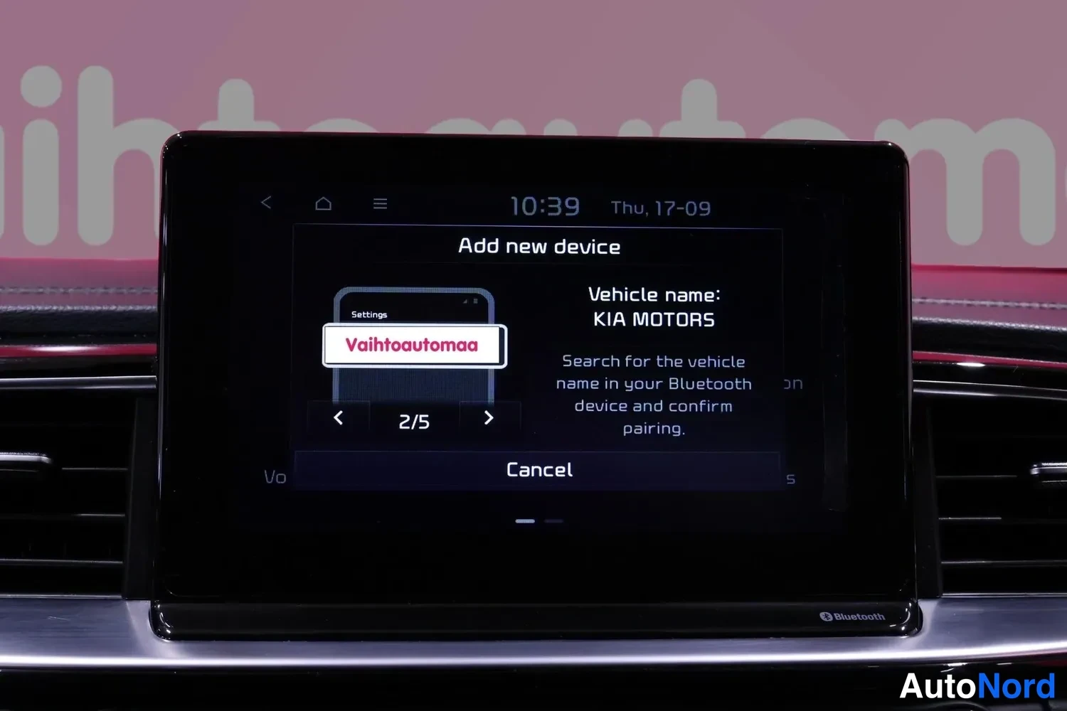 Muu: Auton kojelautaan integroitu infotainment-näyttö näyttää Bluetooth-laitteen lisäysruutua, jossa lukee Vehicle name: KIA MOTORS, kellonaika 10:39 ja päivämäärä T