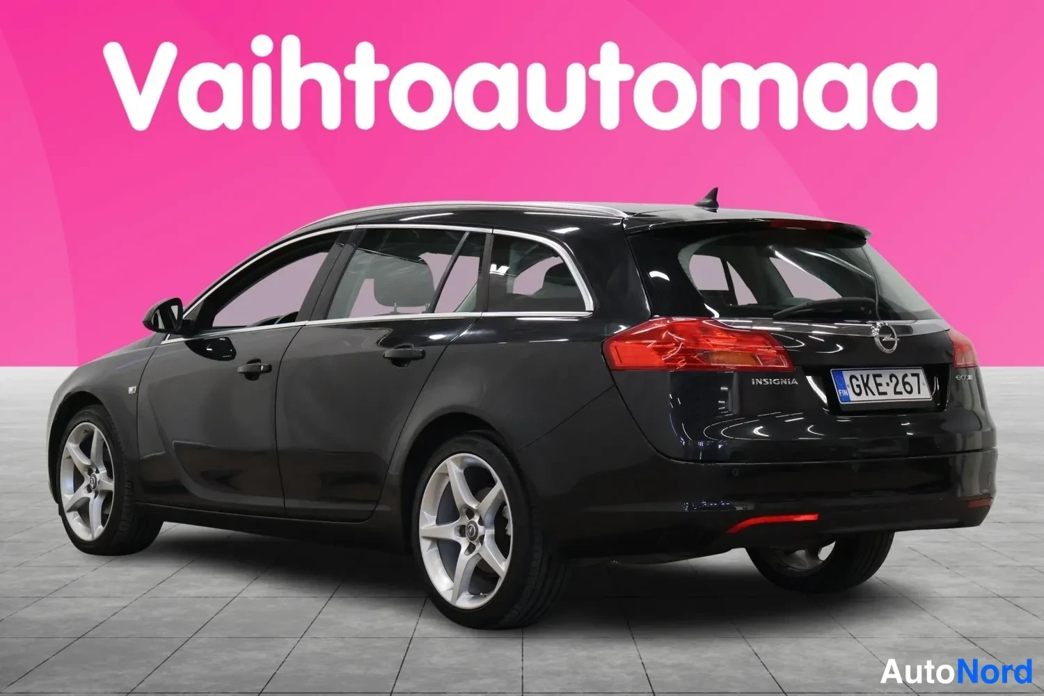 Takaviisto: Mustan farmariauto Opel Insignia Sports takaviistöstä vasemmalta, rekisterikilpi ja takavalot näkyvissä.
