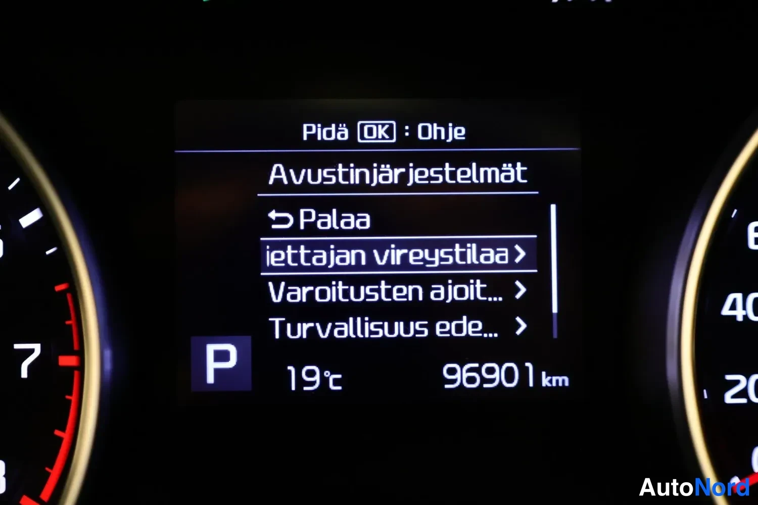 Yksityiskohta: Kojelaudan näyttö: avustinjärjestelmät-valikko, lukema 96901 km, lämpötila 19 °c, P-vaihde.