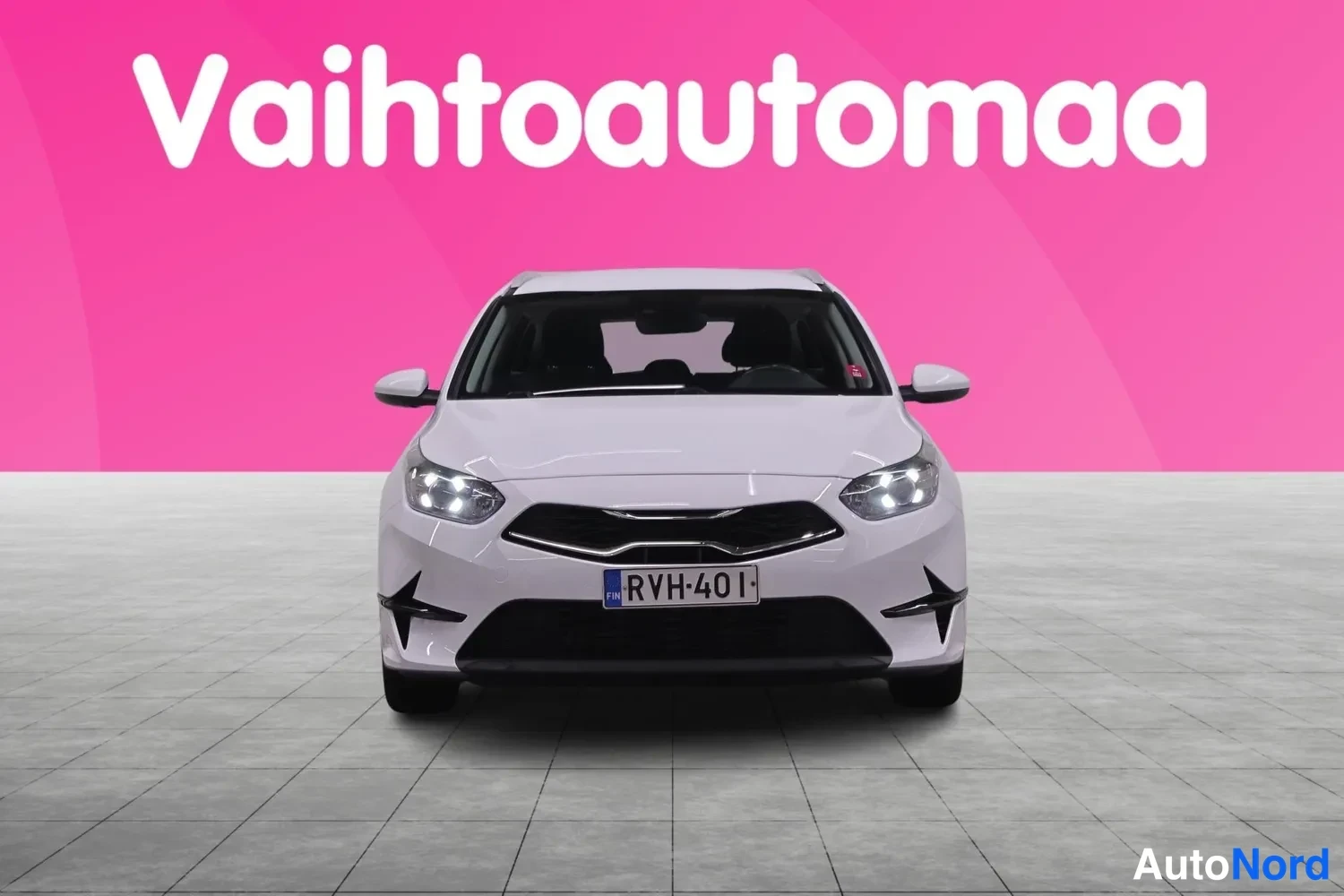 Edestä: Valkoinen farmariauto suoraan edestäpäin, rekisterikilpi, rekkitunnus FIN.