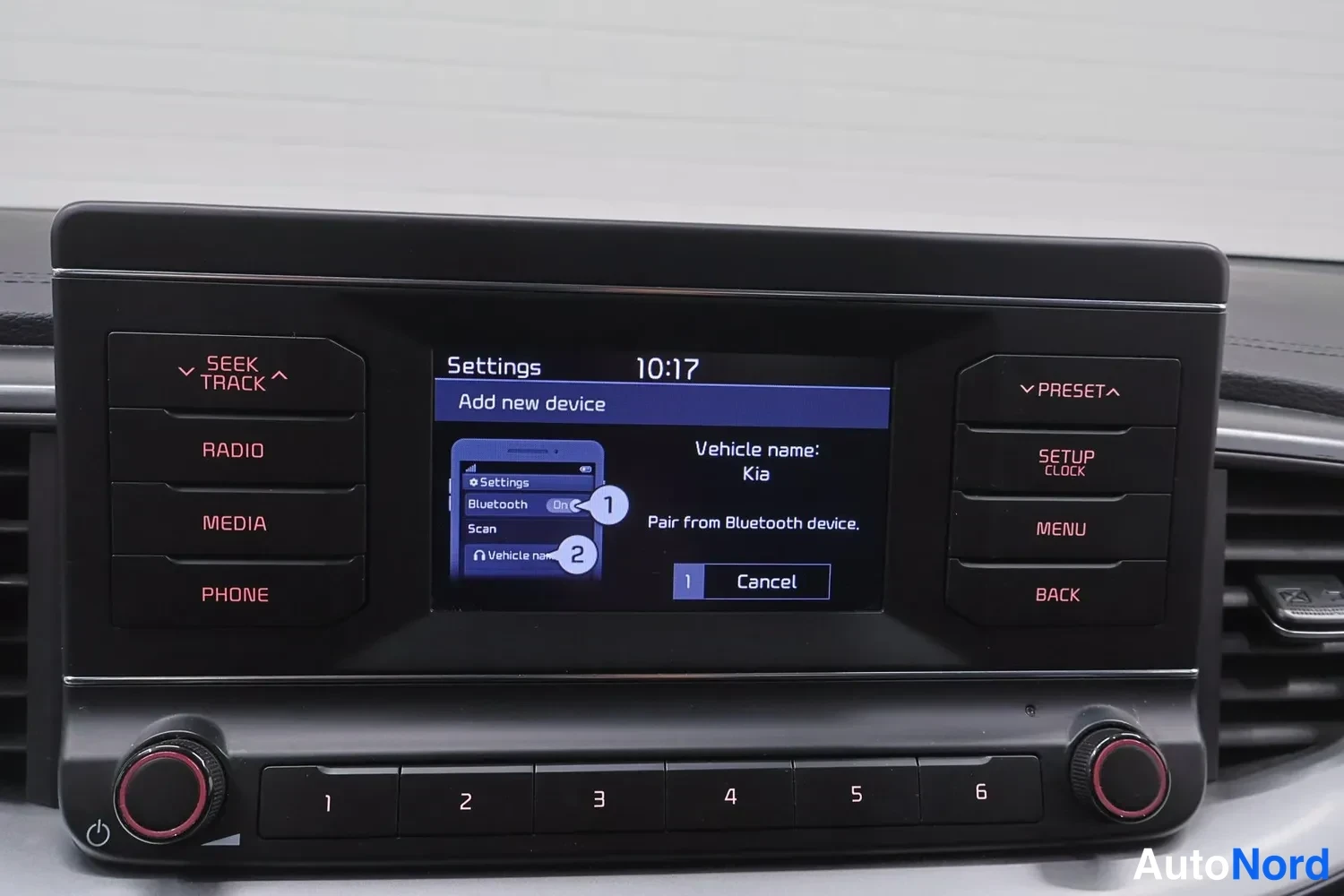 Muu: Kia Ceed 2023: kojelaudan infotainment-yksikön näyttö näyttää Bluetooth-asetuksia, tekstin 'Add new device' ja 'Vehicle name: Kia'. Ympärillä fyysiset painikkee