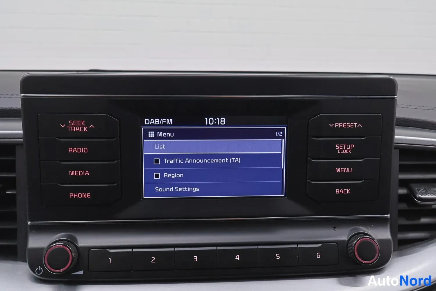 Ohjaamo: Sisäkuva ajoneuvon infotainment-näytöstä ja radio-osasta. Kosketusnäytössä on valikko (DAB/FM) ja aika näytetään. Näkyvissä on radio- ja mediaohjaimet.