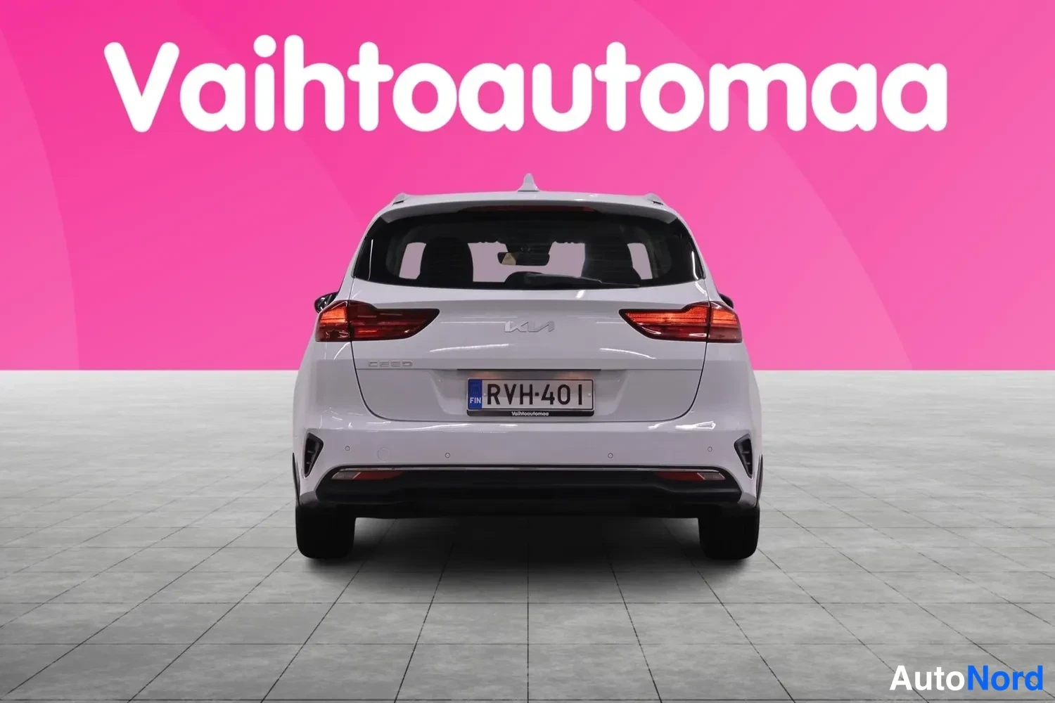 Takaa: Kia Ceed -asema-auto suoraan takaa valkoisena, rekisterikilpi ja punaiset takavalot.